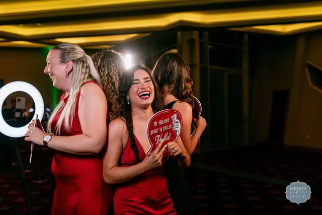 four women laughing and posing for a 360 photo booth in a party
