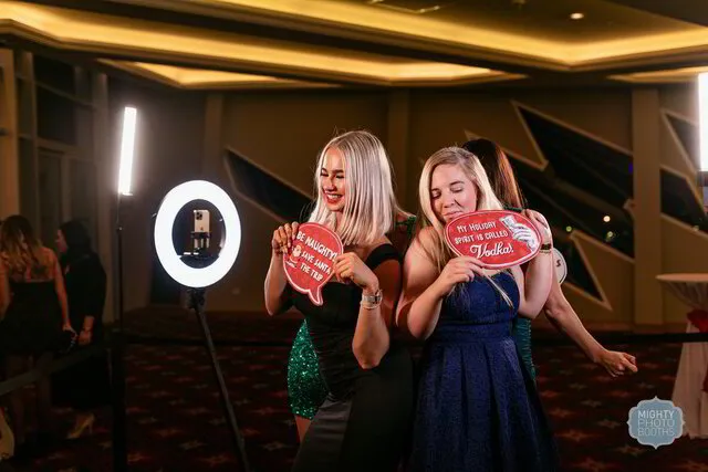 three women holding christmas themed props posing for a 360 photo booth in fort worth texas