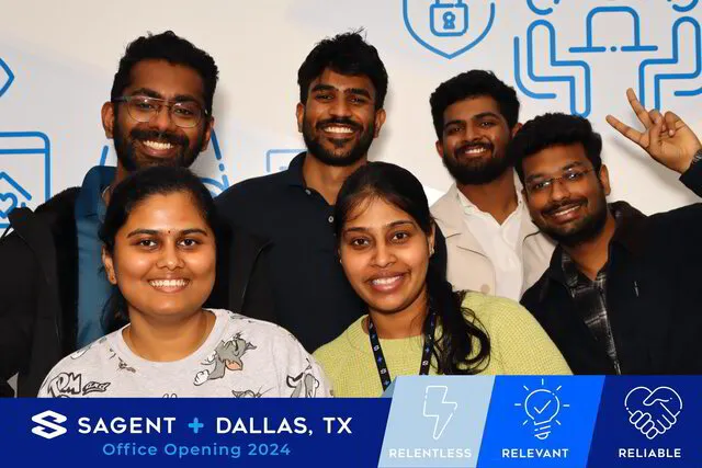 six people smiling and posing for a photo booth in a corporate event with a branded backdrop