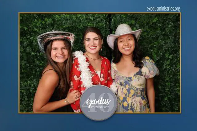 three women wearing hats posing for a photo portrait studio in a corporate event