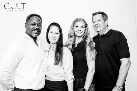 four people posing for a black and white photo booth in a corporate event