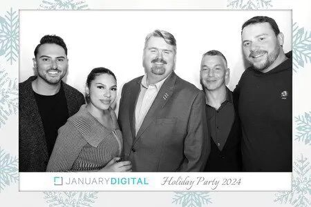 five people posing for a black and white photo booth in a holiday party