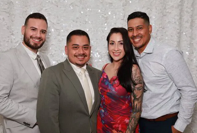 four people posing for an open air photo booth with a white sequin backdrop in a wedding in houston texas