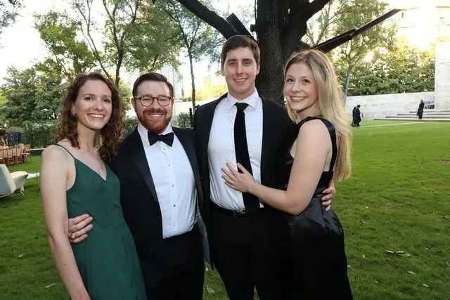 four people smiling for a roaming photo booth in a wedding