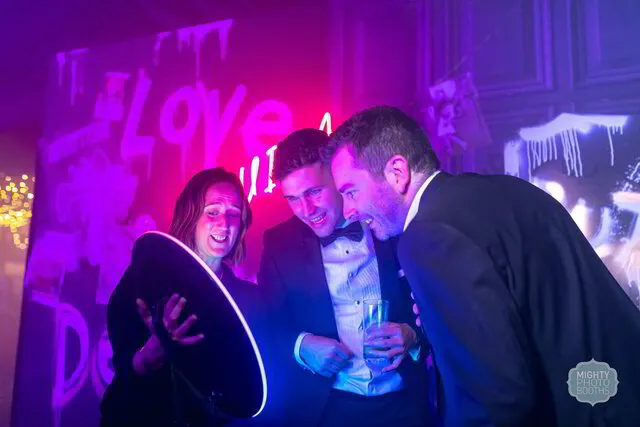 three people exploring the display panel of a roaming photo booth in a party in houston texas