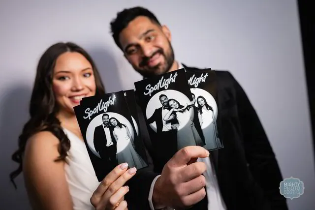 a couple holding prints from a spotlight photo booth